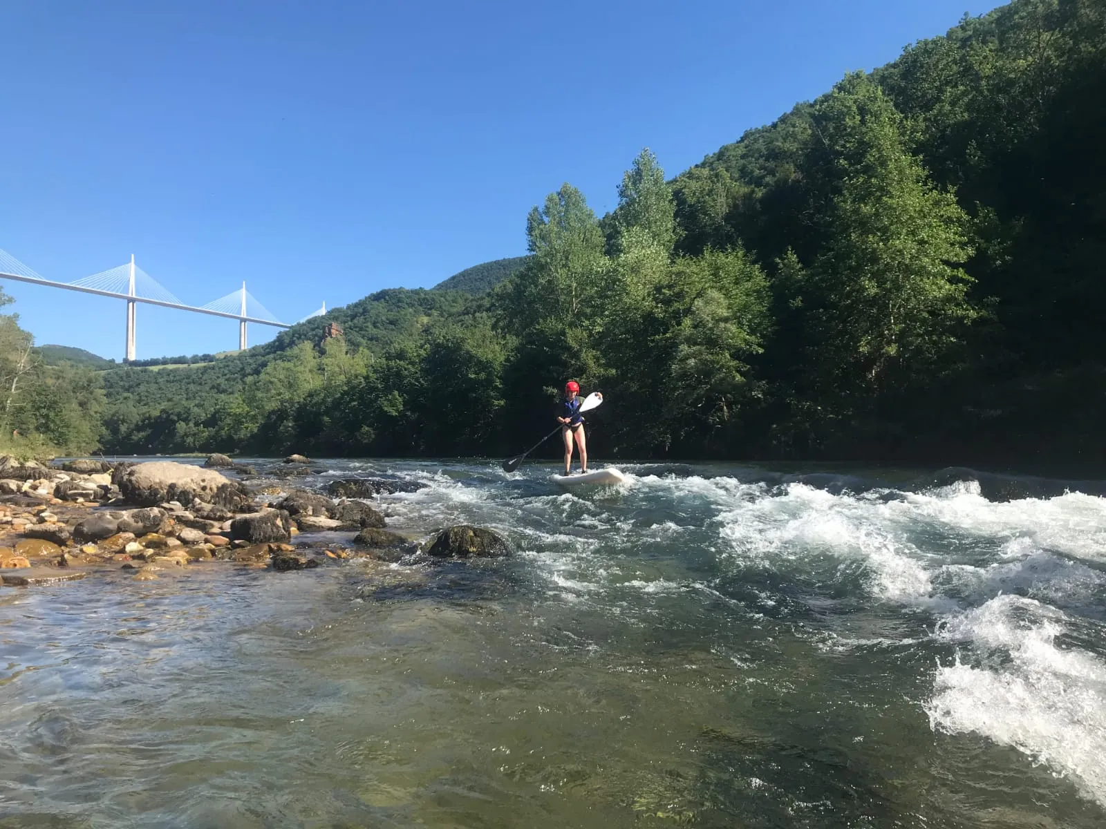Paddle dans un rapide du Tarn, le viaduc de Millau au loin